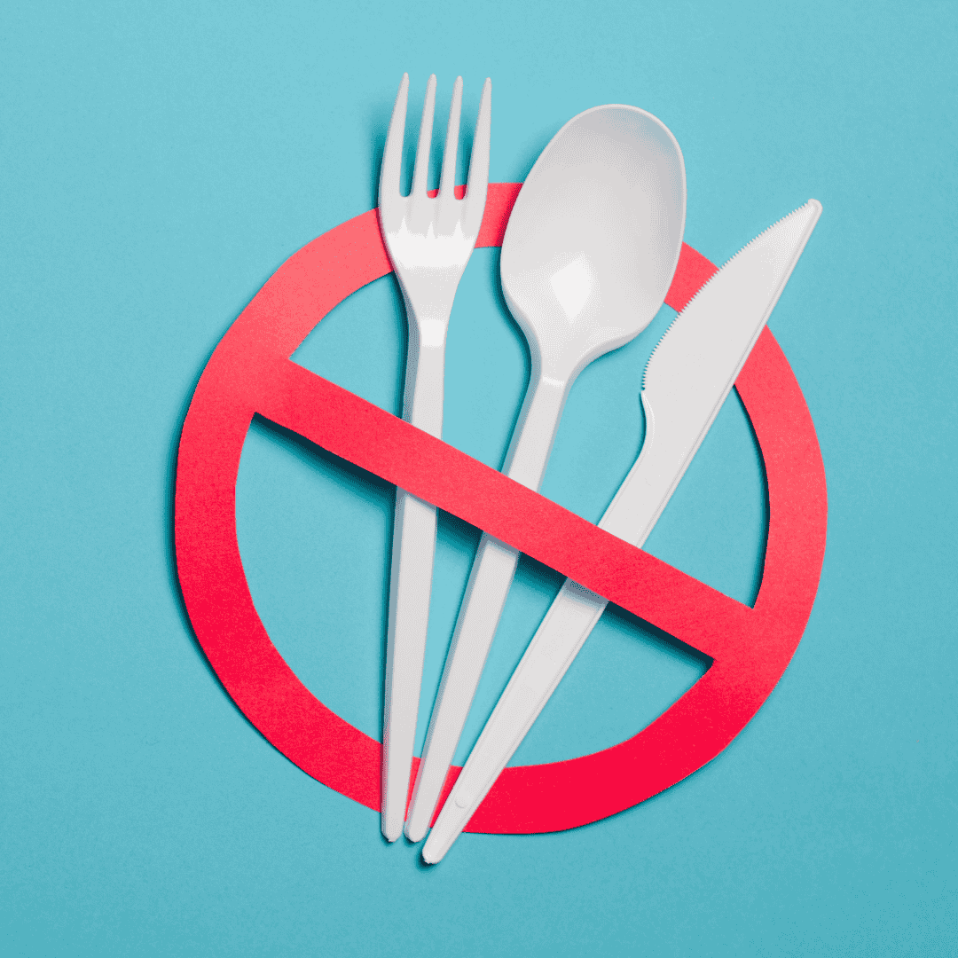 White plastic cutlery, positioned over a red banned symbol on a teal background.