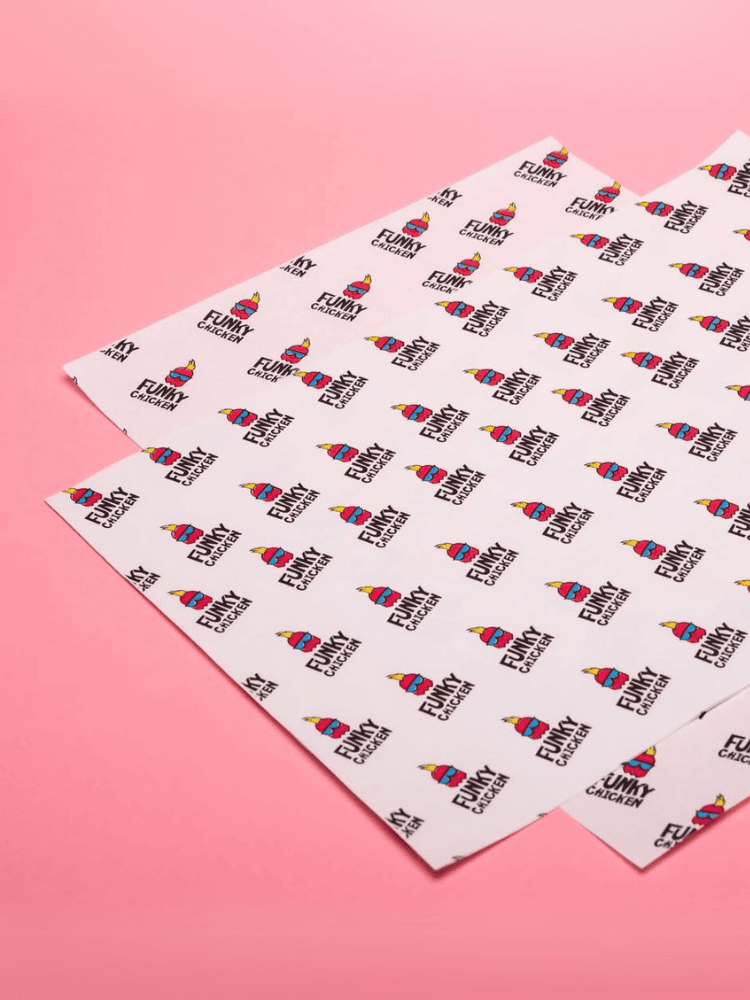 Sheets of white greaseproof paper with a repeating pattern of colourful cartoon chicken and the text Funk Chicken, against a pink background.