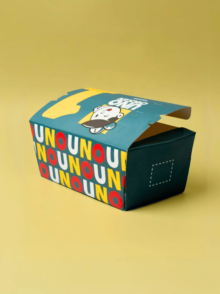 Colourful folded paper box on a yellow background. The box features the repeated word UNO and a cartoon character on the lid.